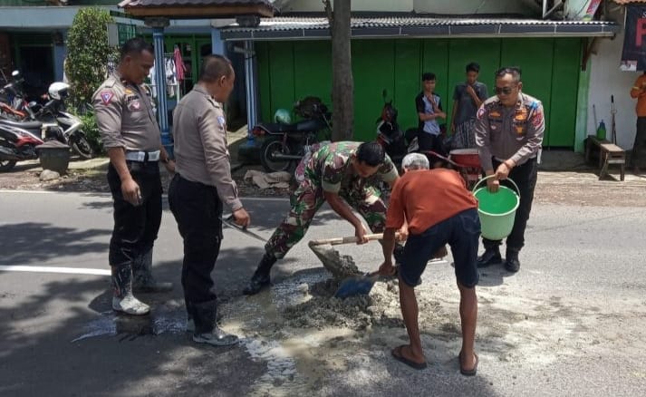 Polisi bersama TNI dibantu warga menambal jalan berlubang di dekat jembatan Tunggulmas Kecamatan Lowokwaru kota Malang